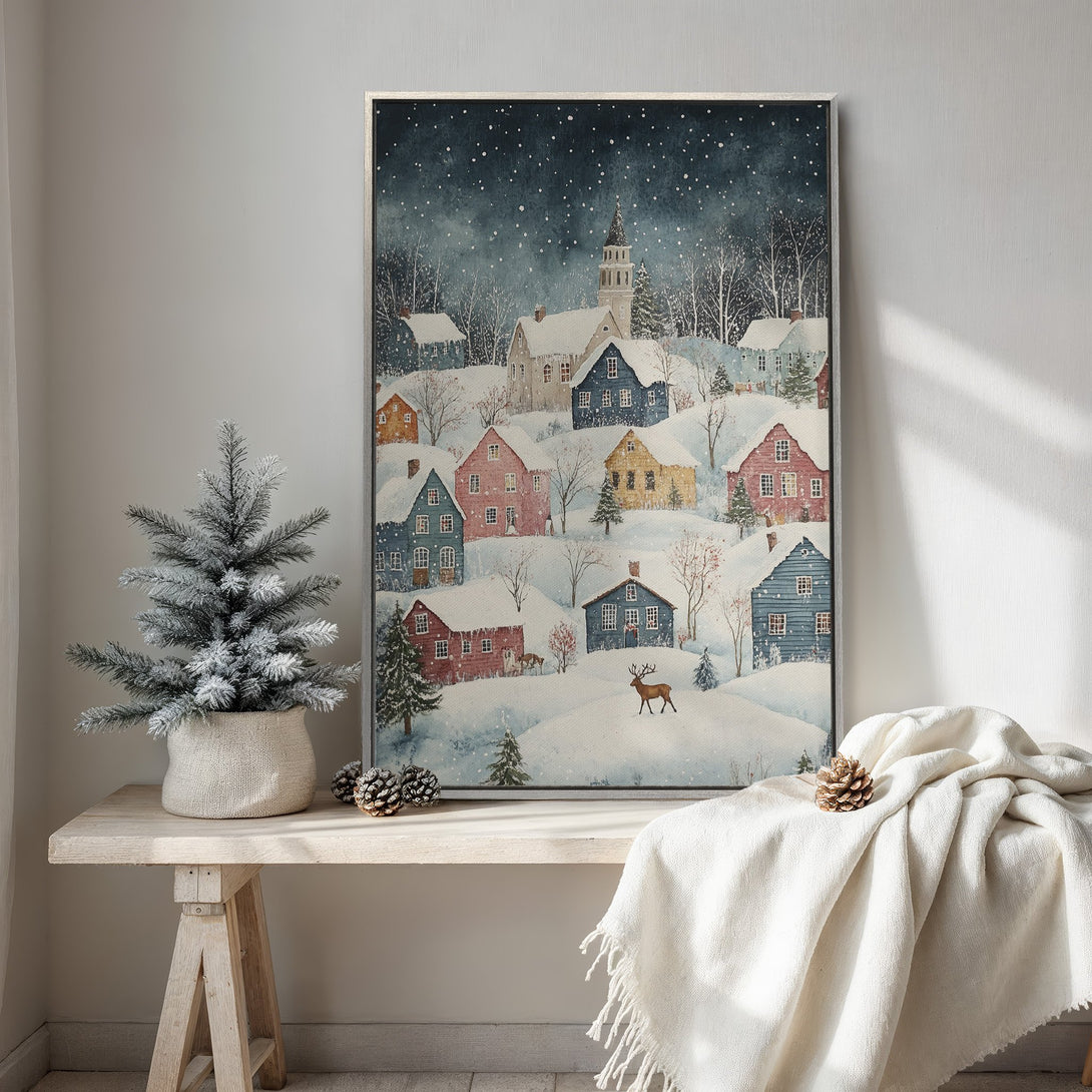 Framed Wall Art featuring a whimsical winter village scene. Watercolor style with a blue, red, and yellow color palette. Perfect for cozy home decor.
