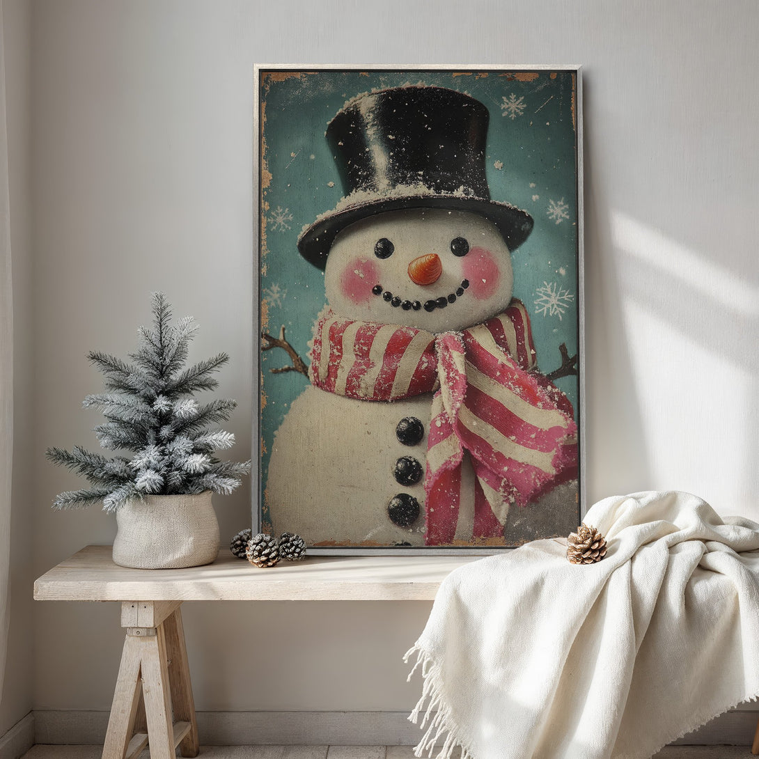 Framed Wall Art featuring a vintage-style snowman with a red and white scarf on a teal background. Perfect for adding a touch of winter charm!