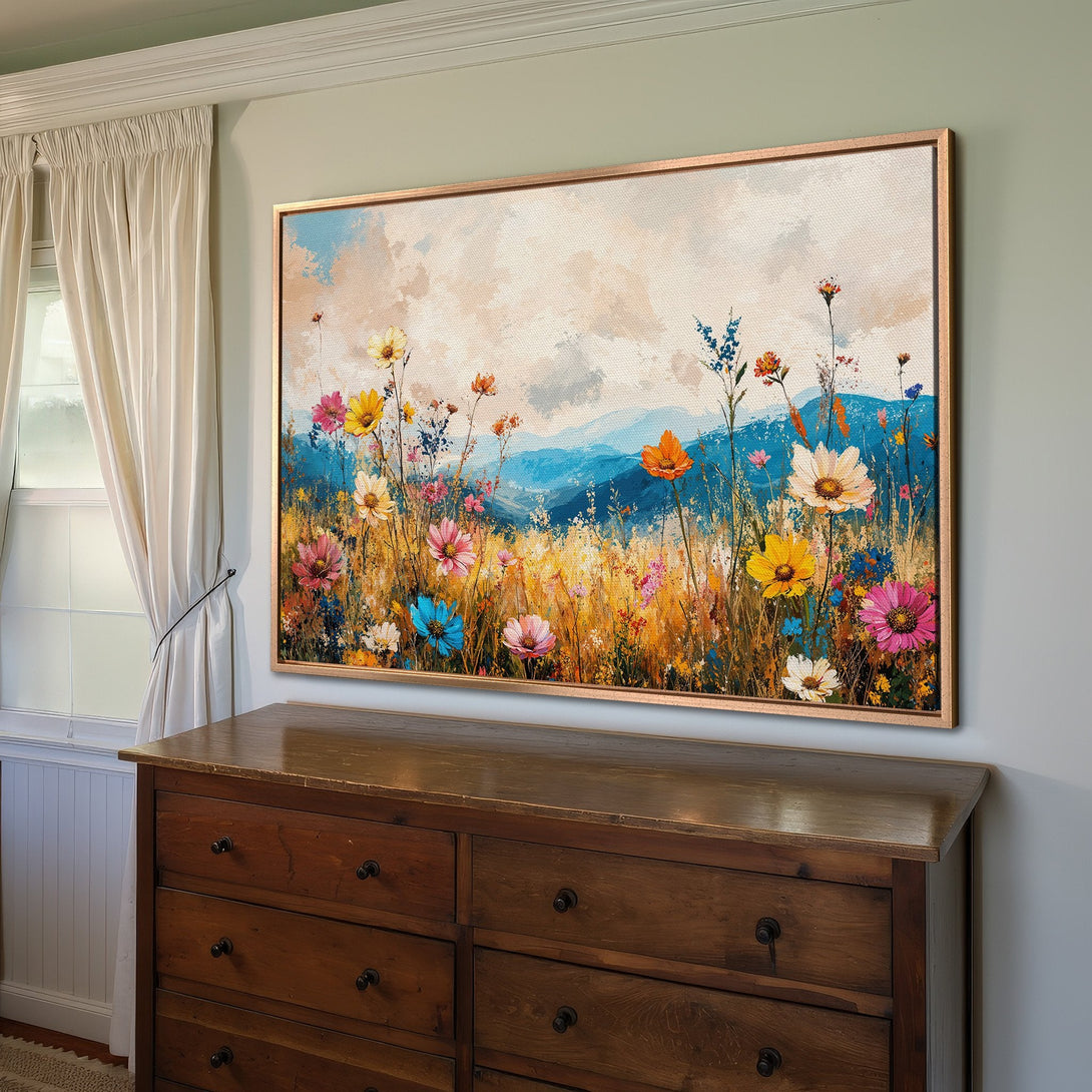 Framed Wall Art: Colorful floral landscape canvas print in a warm, inviting interior. Features vibrant wildflowers and a blue, yellow, and pink color palette.