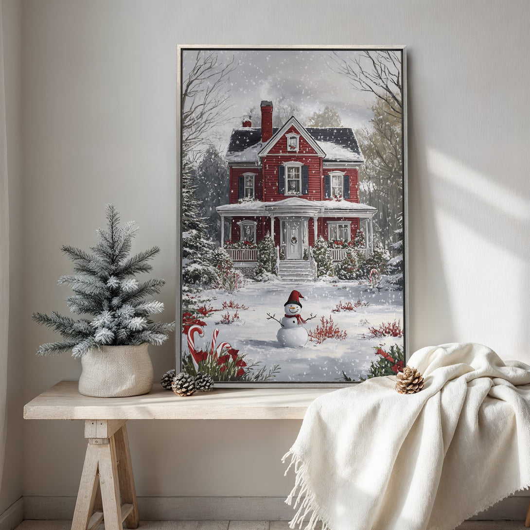 Framed Wall Art featuring a cozy winter scene with a red house, snowman, and snowy landscape. Warm, inviting color palette perfect for holiday decor.