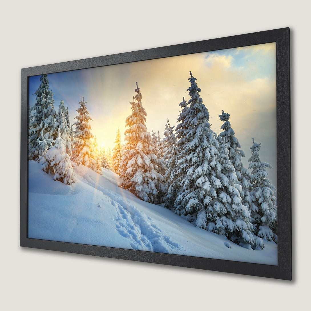 Framed Poster of a snowy winter landscape with pine trees, warm sunlight, and a blue/white/yellow color palette.