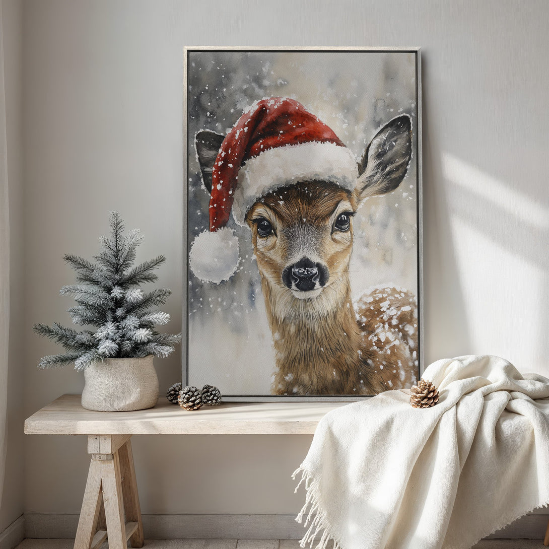 Framed Wall Art: Watercolor painting of a deer wearing a Santa hat. Neutral color palette with pops of red, perfect for Christmas decor.