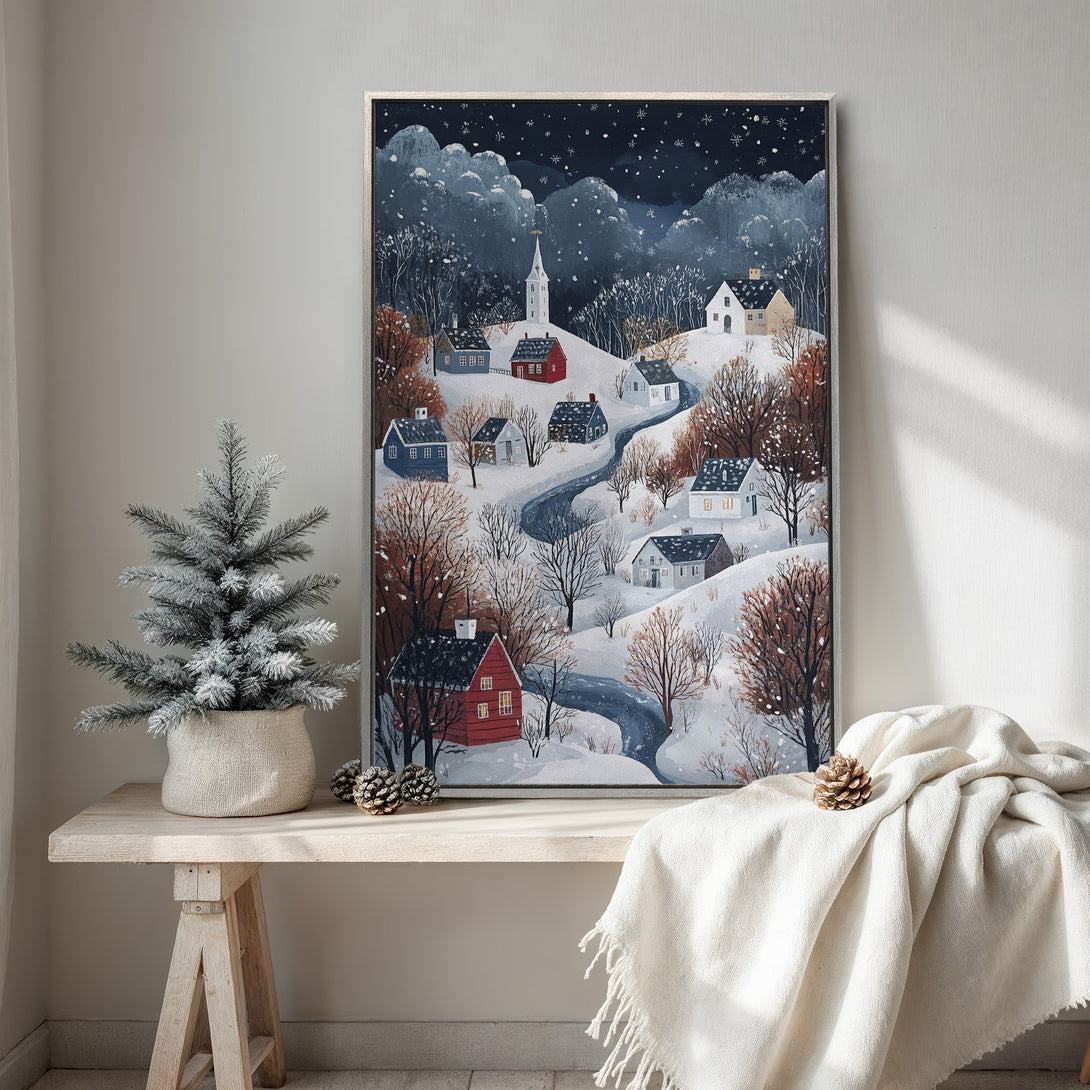 Framed Wall Art: Winter village scene in a cozy, watercolor style. Features snowy landscape with blue, white, and red hues. Perfect for adding warmth to your home.