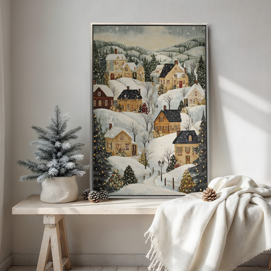 Framed Wall Art featuring a charming winter village scene in a cozy, painterly style. Soft, neutral color palette with pops of festive red and green. Perfect holiday decor.
