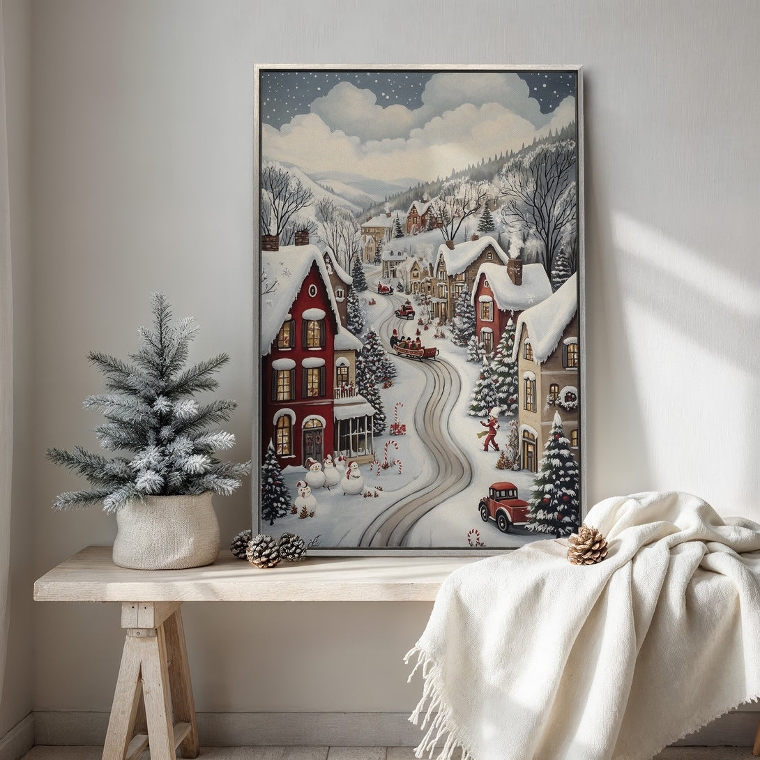 Framed Wall Art: Winter village scene canvas print in a cozy interior. Featuring a charming, whimsical style with red, white, and blue tones. Perfect holiday decor!
