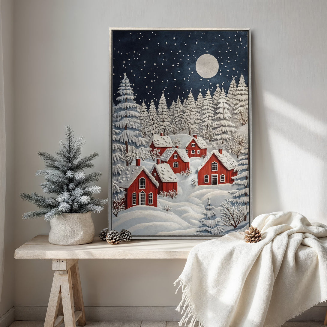 Framed Wall Art featuring a winter village scene with red houses, snowy landscape, and a dark blue night sky. A cozy, festive canvas print for your home.